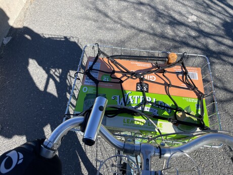Two 12-packs of seltzer in the front basket of a bike