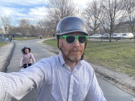 Selfie of me in helmet and green sunglasses in foreground, girl with black hair on her own bike in background 