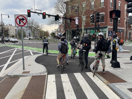 Six bicyclists waiting at a red light in a protected area ahead of a crosswalk 